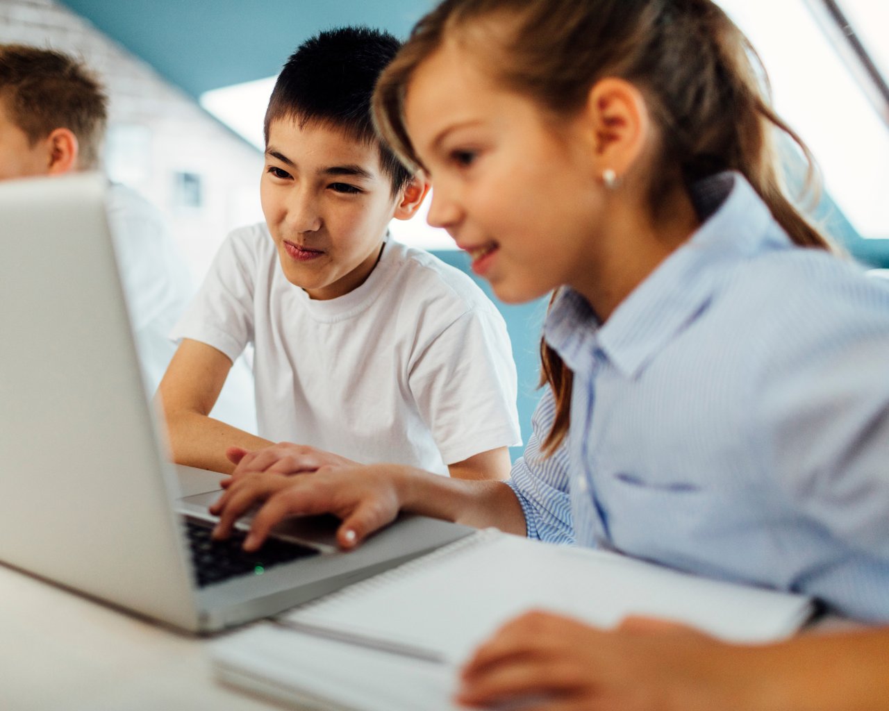 Two school-aged children working together on a laptop, engaged in learning and collaboration, in a bright and supportive environment.