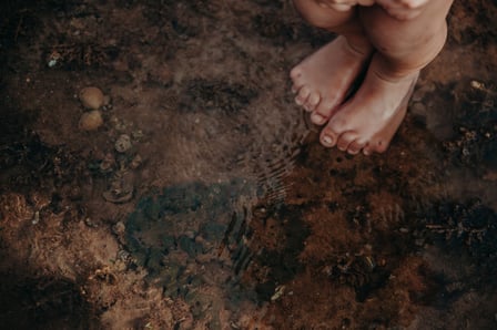 A young Aborginal person's feet standing in a creek.