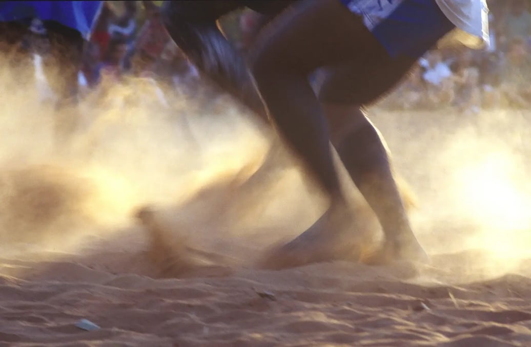 Aborginal people dancing in the red dirt.