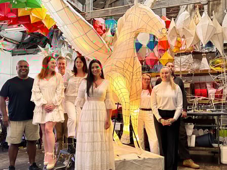 A group of CASPA staff dressed in white stand with the large pegasus lantern, ready to walk in the parade.