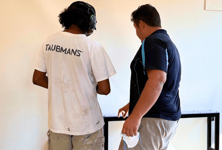 A young person works on a home interior with his mentor.