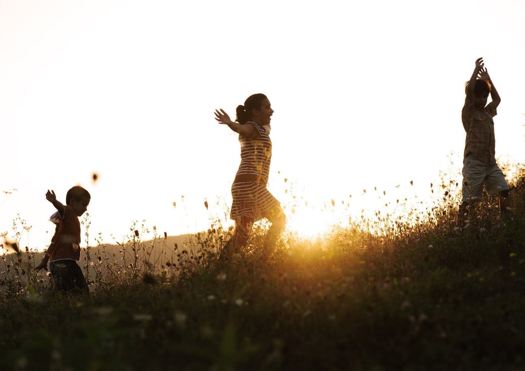 Children happily running together outside at sunset.