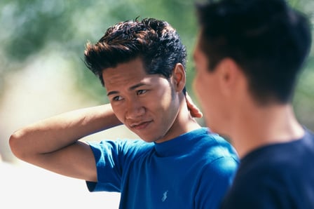 A young person in supported conversation with an adult in a bright outdoor setting.