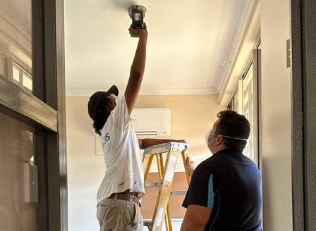 A young person and their mentor working together to complete maintenance work in a home.