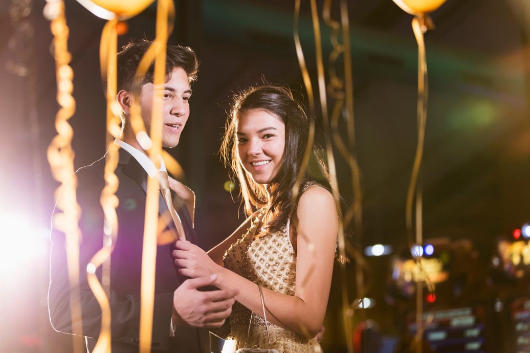 A young couple in formal attire dance together surrounded by balloons. They are happy..