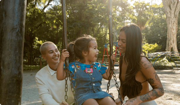 A happy, diverse, same sex couple with a young child enjoying time together at a playground.